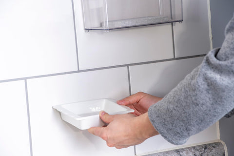 Person using Max Strength Construction Adhesive Crystal Clear Two And A Half Ounce Squeeze Tube Waterproof Gap Filling on a tile wall.