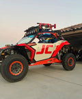 Red and white off-road vehicle with 33 Inch Ratcheting Off Road Utility Farm Jack 3 Ton Capacity attached on garage driveway