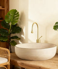 Retro Oval Ceramic Vessel Sink for Bathroom Vanity, modern minimalist oval sink on wooden counter with brass faucet and greenery.