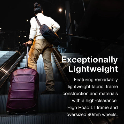 Osprey Ozone 2-Wheel carry-on luggage in burgundy with extended trolley handle on escalator.