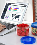 Sixteen Ounce Freezer Storage Containers Set With Twist Top Lids filled with strawberries and kiwi near laptop