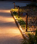 Low Voltage Outdoor Pathway Lighting Kit With 0.6W LED 3100K Warm White 12V Metal Path Lights In Charcoal Brown 8 Pack With Connectors And Stakes Durable Yard And Garden Landscape Accent Lighting illuminating a garden path