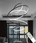 Modern Led Pendant Light With Remote Dimmer And Chill Warm Glow For Living Room Dining Area And Kitchen Contoured Gold Ceiling Hanging Lamp Featuring Four Rings And Dead Simple Setup in black finish suspended from ceiling.