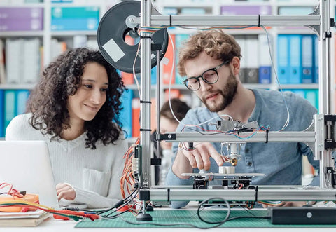 Two people discussing next to a 3D printer with 10 Pack 48 Inch T Slot Aluminum Extrusion 2020 European Standard used for assembly.