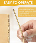 Close-up of hand holding brass leather needle, threading leather, for Two Piece Brass Leather Sewing Needles For Hand Stitching And Lacing, Long Jumbo Lacing Needles Set, Fits Flat Leather Cord Up To 4mm, Manual Threading Tool For Leather Crafting And DIY Projects.