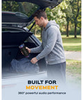 Man placing Waterproof Bluetooth Speaker 30W With 360 Degree Sound And Deep Bass IPX7 TWS into car trunk, outdoors.