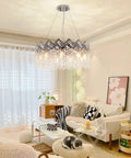 Dope Modern K9 Crystal Chandelier With Nine Lights Raindrop Pendant Ceiling Light Chrome Finish illuminating a cozy living room.