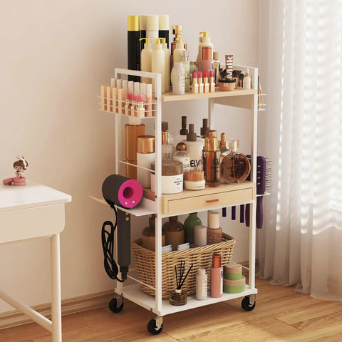 Three Tier Rolling Utility Cart With Wooden Drawer in white used as makeup storage, with cosmetics and bottles displayed on tiers