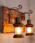 Industrial Farmhouse Wall Sconce Lighting Fixture With Wooden Base And Two Lantern Lights, warm glow on wooden wall.