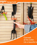 Hand placing tool on Six Pack Heavy Duty Garage Hooks 2.8 Inch U Shaped Wall Mounted Hanger For Ladders Hose Tools And Bulk Items Organization Steel With Non Slip Rubber Coating.