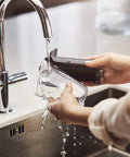 User rinsing LatteGo milk frother under faucet while holding a glass, showcasing the Fully Automatic Espresso Machine With Killer LatteGo Milk Frother And True One Touch Cappuccino Setup For Straight Up Home Coffee Perfection In Sleek Black Certified Refurbished.