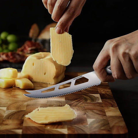 Five Inch Serrated Cheese Knife Crafted With Premium Steel Core And A Super Slick Hollow Blade For Butter Smooth Cuts That Slide Off Easy Plus A Gotta Have Fork Tip For Zero Mess Party Spread cutting cheese on a wooden board.