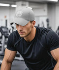 Man wearing Men's Dope Breathable Light Gray Tennis Cap, lightweight adjustable baseball hat with soft comfort in gym setting.