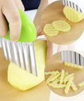 Two-pack stainless steel crinkle cutter with green ergonomic handle slicing a potato into crinkle-cut fries.