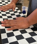 Applying Ultra Sticky 9 By 33 Grip Tape with checkerboard design on longboard using Easy Apply Adhesive.