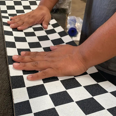Applying Ultra Sticky 9 By 33 Grip Tape with checkerboard design on longboard using Easy Apply Adhesive.
