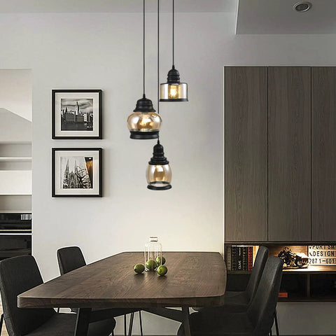 Three Light Modern Glass Pendant Chandelier for Dining Room and Kitchen Island with Amber Glass Shades hanging over table.