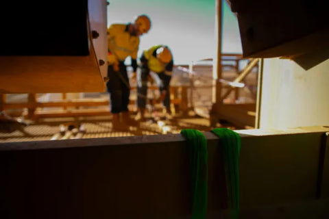 Green Round Lifting Sling Strap 50 mm By 4 Ft Endless Webbing Heavy Duty Lift Sling in construction site with workers in background
