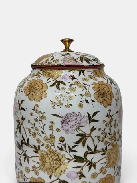 Floral patterned ceramic jar with lid and gold accents on white background.