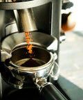 Barista Level Electric Coffee Grinder With Stepless Control And 54Mm Steel Flat Burrs delivers grounds into a portafilter.