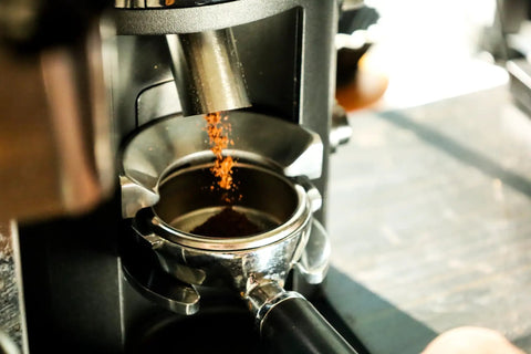 Barista Level Electric Coffee Grinder With Stepless Control And 54Mm Steel Flat Burrs delivers grounds into a portafilter.