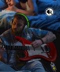 Man using Compact 5W Guitar Headphone Amp With Built In DSP Distortion Timbre For Electric Guitars while playing red guitar.