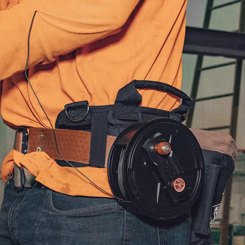Person wearing a Tie Wire Reel With Quick Lock And Lightweight Aluminum Body, Ambidextrous Rewind Knob, for 12 to 18 Gauge Wire