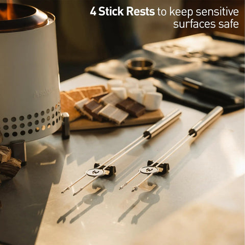 Tabletop view of Mesa Outdoor Fire Pit Accessory Pack With 4 Stainless Steel Mini Sticks Stick Rests on a table.