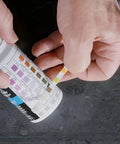 Person holding Real Down To Earth Five In One Water Quality Test Strips For Pools And Spas to test water quality.