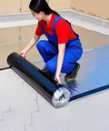 Woman applying Tough As Nails Asphalt Waterproof Repair Tape Heavy Duty Self Adhesive Aluminum Foil on cracked surface.