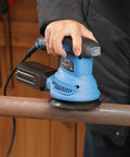 Beefy 4.9 Inch Random Orbital Sander Corded Power Tool With Full 20 Piece Sandpaper Roll Kit in use on a metal surface.