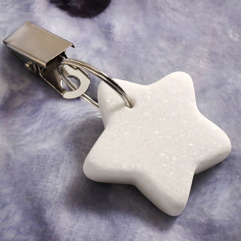 Star-shaped marble weight with stainless clip from 10 Pack Marble Tablecloth Weights With Clips on fabric background.