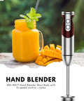 Powerful 12 Speed Immersion Blender With Durable Stainless Steel Blades For Smooth Soups And Thick Shakes next to a fruity drink and mango slices.