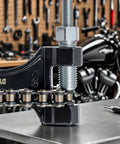 Close-up of a 420 Chain Kit 132 Links Cut To Fit With Master Links Breaker Tool on a workbench in a garage setting.