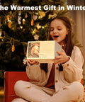 Girl holding Cozy Heated Mouse Pad Hand Warmer gift box by Christmas tree, showcasing product packaging.