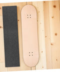 Two Pack Black Skateboard Grip Tape Sheets 33 Inch By 9 Inch Anti Skid Sandpaper next to wooden skateboard deck