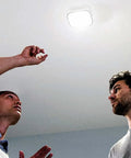 Two men installing Bright 1000 Lumens LED Garage Light With Quick Mount And No Fuss Setup Ceiling Or Wall Mount App Control And Scheduling