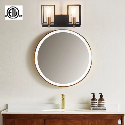Two Light Over Mirror Bathroom Light Fixture In Rustic Farmhouse Style Industrial Metal Cage Wall Sconce With Matte Black Frame And Antique Brass Accents 14.56 Inch Length Dope Vintage Vanity Lighting For Bathrooms shown above a round mirror.