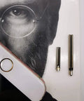 Pro Grade Headphone Jack Removal Tool Set with 20mm and 30mm stainless steel tubes placed next to a phone on a book
