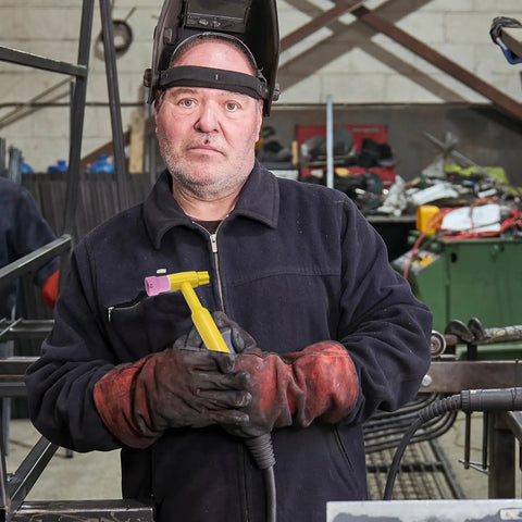 Man in gloves holding pink TIG welding torch with sturdy ceramic nozzle, showcasing Rock Solid Pink Tig Welding Cups That Make Cleaning A Breeze.
