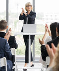 Woman standing at a podium using Go To Mobile Rolling Laptop Desk With Two Lockable Wheels Height Adjustable Sit Stand Computer Workstation.