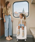 Child sitting on ride-on suitcase with mother nearby, showcasing Underseat Carry On Luggage For Kids With Wheels TSA Approved Ride On Suitcase