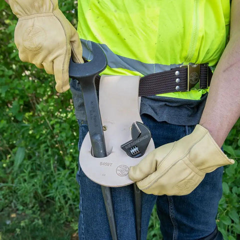 Worker wearing leather riveted spud wrench holder with tunnel connection for dual spud wrenches and adjustable head construction wrench.