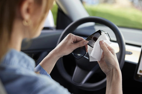 ZEISS sunglasses cleaning wipes, pre-moistened, 240-count; hands cleaning sunglasses in car.