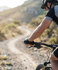 Cyclist using 7 Speed Right Thumb Bike Shifter For Smooth Gear Changes on mountain trail, close-up showing gear indicator.