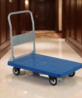 Heavy Duty Folding Transport Cart With Aluminum Handle And Rugged Deck For Easy Box Hauls In Warehouses Labs And Classrooms Four Wheel Push Cart For Daily Use And Reliable Smooth Mobility blue deck with folded handle in hallway
