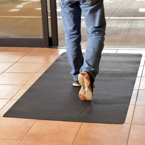 Person stepping on black Indoor Outdoor Rubber Scraper Mat For High Traffic Areas 36 Inch By 6 Foot Black Heavy Duty Doormat