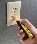 Straight Up Tough Non Contact Voltage Detector 50 To 1000 Volt Ac used on electrical outlet with ergonomic grip in hand.