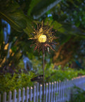 Sun Powered Solar Garden Light Stake With Crackle Glass Metal Finish glowing in a garden at night.