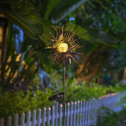 Sun Powered Solar Garden Light Stake With Crackle Glass Metal Finish glowing in a garden at night.